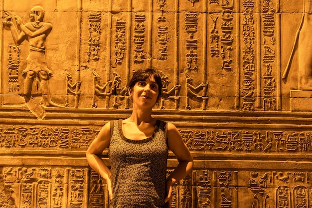 Una mujer joven mirando dibujos y jeroglíficos egipcios en el Templo de Kom Ombo