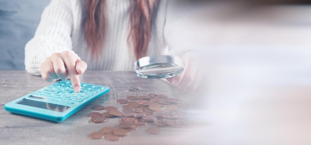 Mujer joven mirando dinero con una lupa