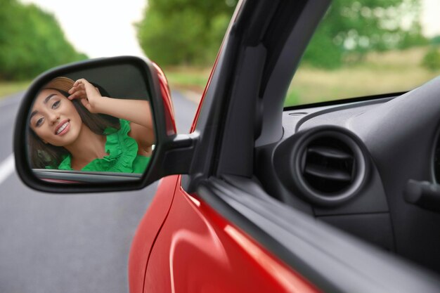 Mujer joven mirando en el espejo retrovisor del coche