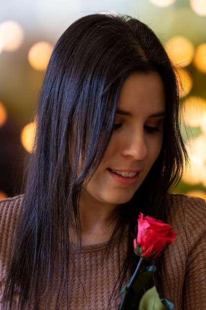 Mujer joven mirando felizmente una flor color de rosa