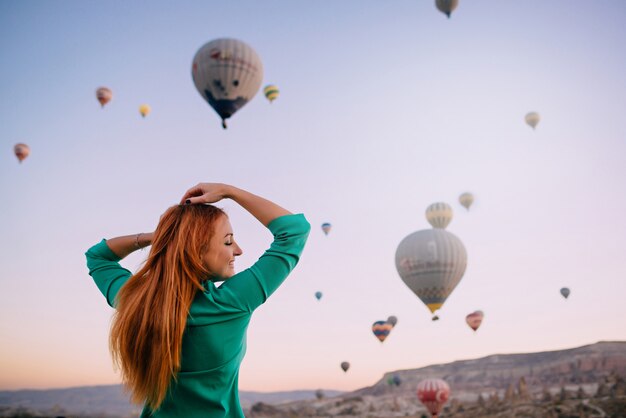 Mujer joven mirando globos brazos extendidos