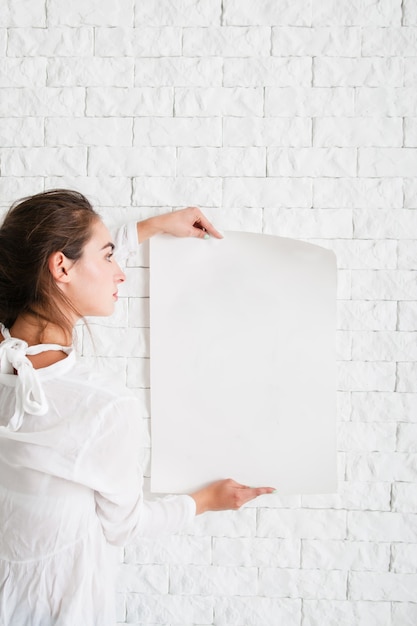 Foto mujer joven mirando la hoja de papel vacía