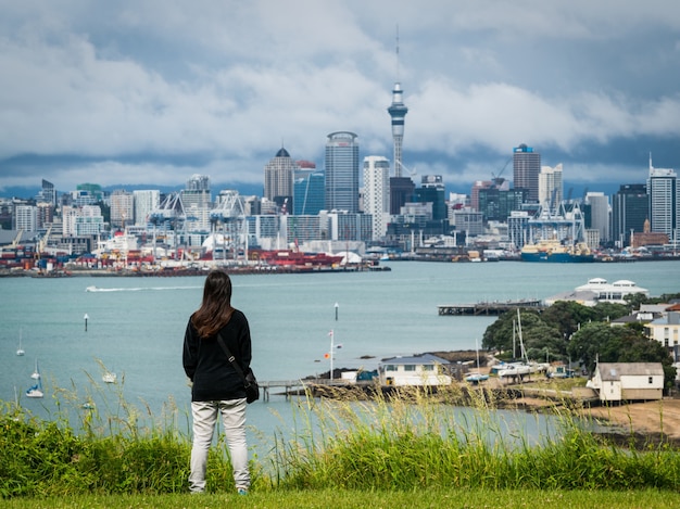 Mujer joven mirando el horizonte de la ciudad de auckland