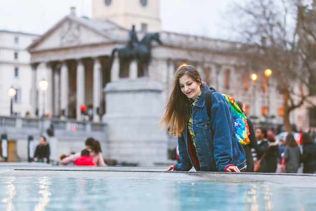 Mujer joven mirando a sí misma en una fuente en Londres