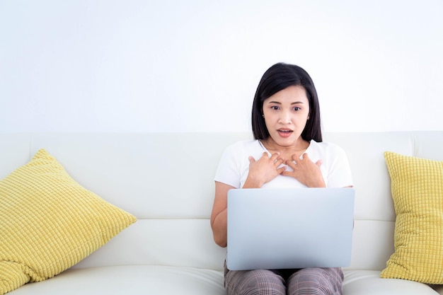 Mujer joven mirando su computadora portátil con expresión de gran conmoción en la cara Expresión sorprendida