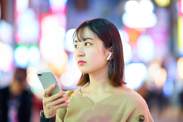 Mujer joven mirando el teléfono inteligente por la noche