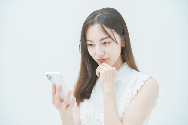 Mujer joven mirando un teléfono inteligente con sentimientos desagradables