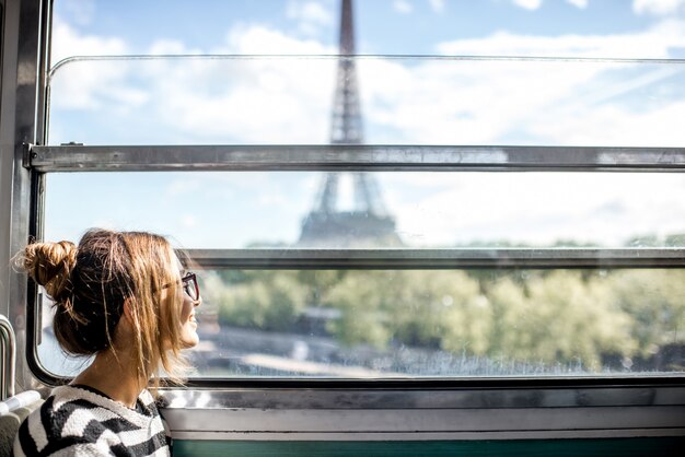 Mujer joven mirando a la torre Eiffel a través de la ventana del tren en París