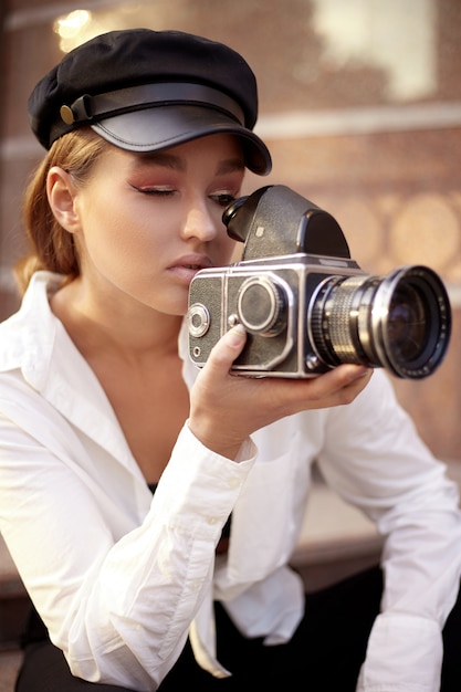 Mujer joven mirando a través de la lente de la cámara