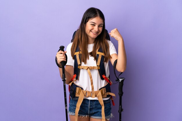 Mujer joven con mochila y bastones de trekking