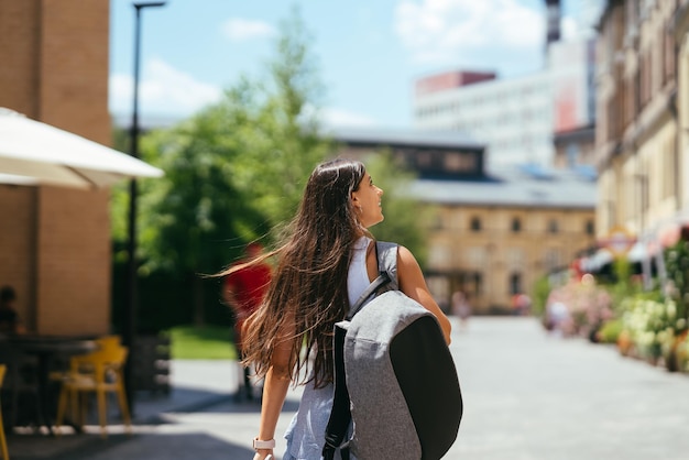 Mujer joven con mochila camina por la ciudad