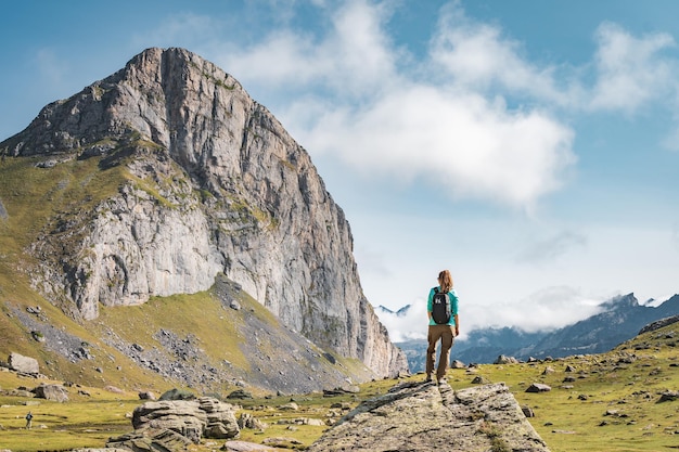 Foto mujer joven con una mochila en la cima de una roca en un hermoso concepto de destino de viaje