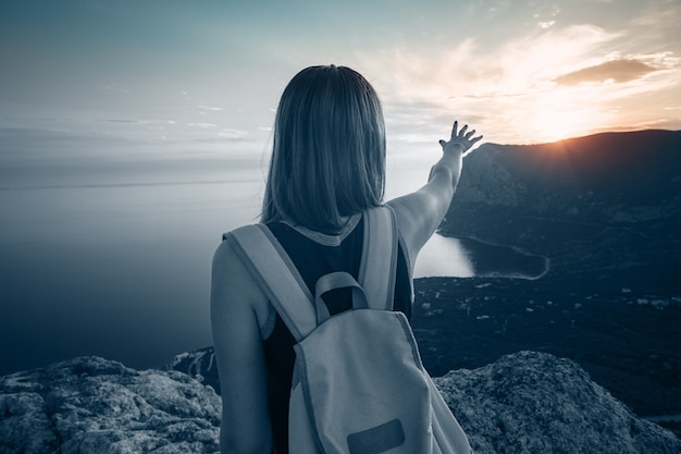 Mujer joven con mochila disfruta de la vista de las montañas y el mar al atardecer. Estilo de vida concepto emocional vacaciones escapada de fin de semana aérea Crimea paisaje