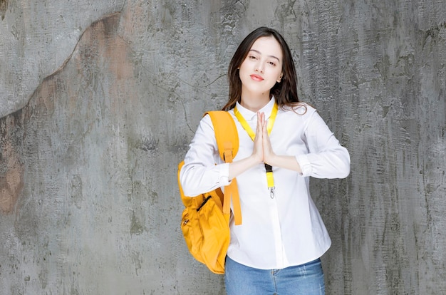 Mujer joven con mochila de pie sobre la pared. foto de alta calidad