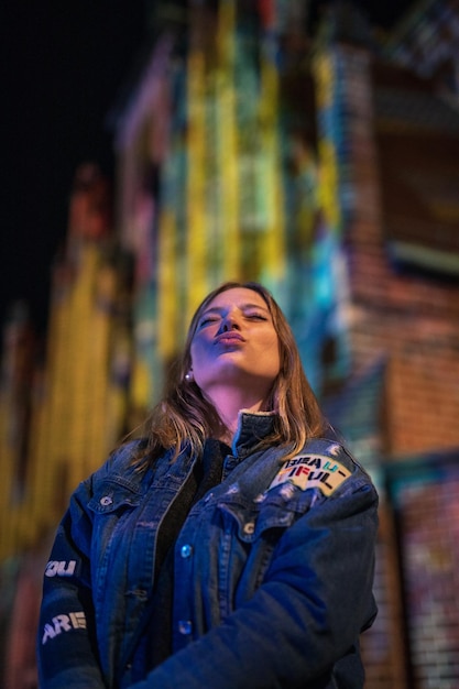 Foto mujer joven a la moda en la ciudad por la noche