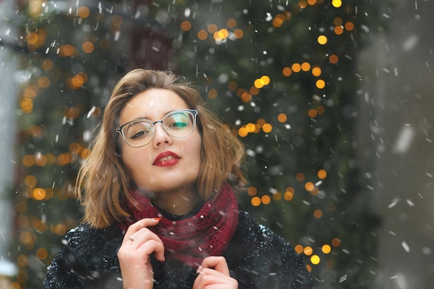 Mujer joven de moda disfrutando de las nevadas en las vacaciones de Navidad. Espacio para texto