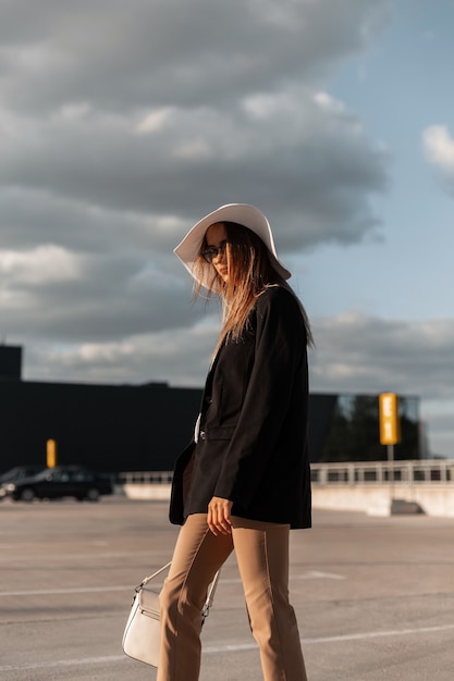 Mujer joven de moda elegante con bolso en casual elegante y sombrero de camina
