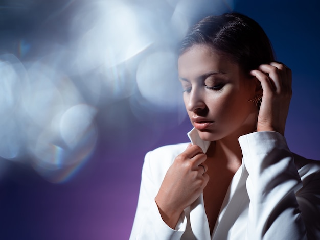 Mujer joven de moda elegante en retrato dinámico blanco a través de facetas de cristal