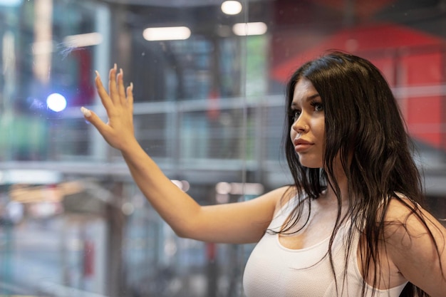 Mujer joven a la moda de pie junto a la ventana