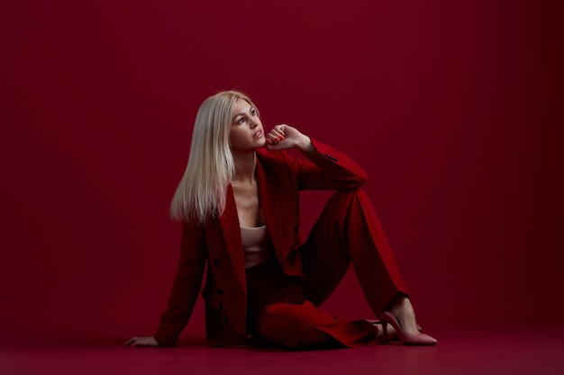 Foto mujer joven de moda en traje rojo fondo rojo