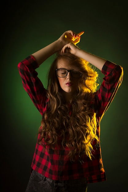 Mujer joven de moda en vasos en la oscuridad