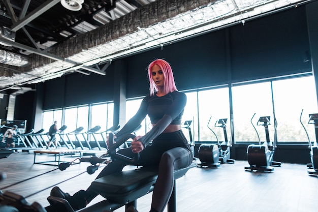 Mujer joven modelo de deportes trabajando y haciendo ejercicio en la máquina en el gimnasio