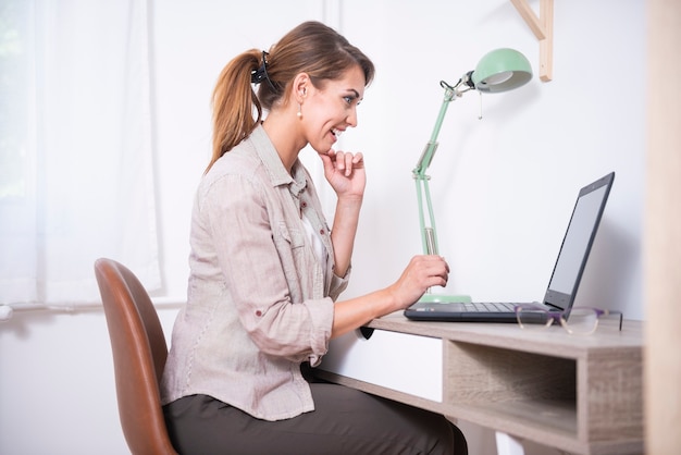 Mujer joven moderna trabajando de forma remota desde casa