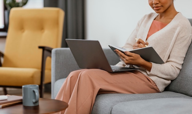 Mujer joven moderna trabajando mientras está sentado en el sofá