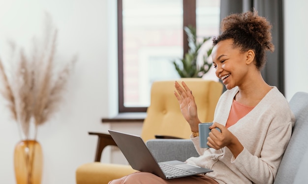 Mujer joven moderna trabajando mientras está sentado en el sofá