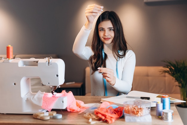 Mujer joven modista cose ropa en máquina de coser