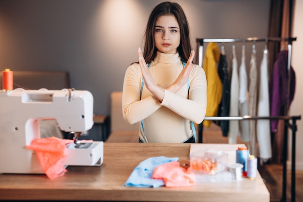 Mujer joven modista cose ropa en máquina de coser