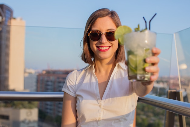 mujer joven con un mojito en la azotea.