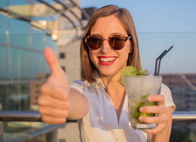 mujer joven con un mojito en la azotea.