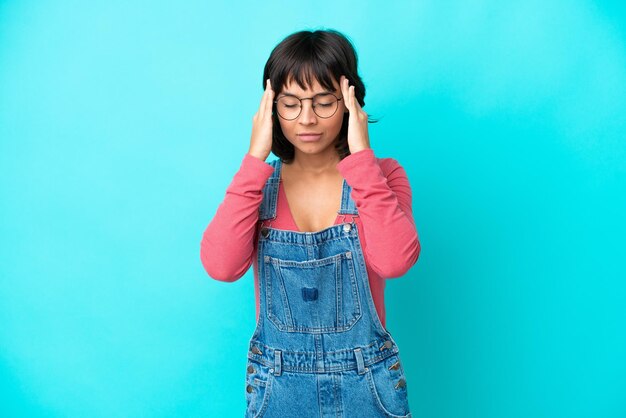 Mujer joven con un mono de fondo aislado con dolor de cabeza