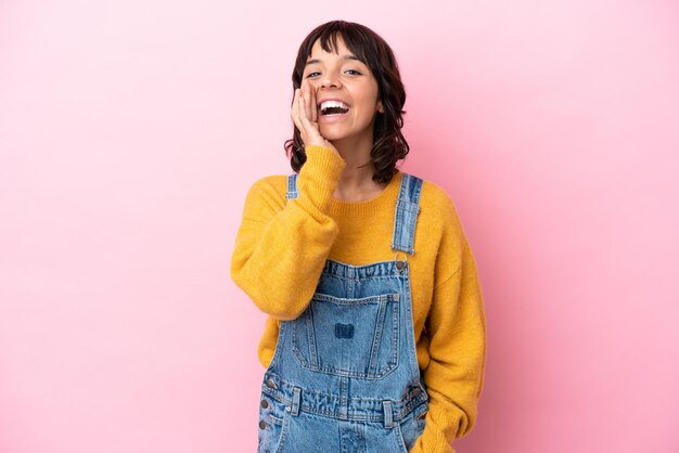 Mujer joven con un mono de fondo aislado gritando con la boca abierta