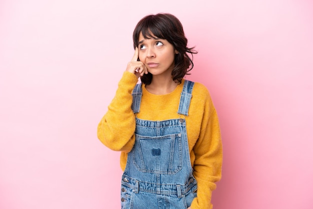 Mujer joven con un mono de fondo aislado pensando en una idea