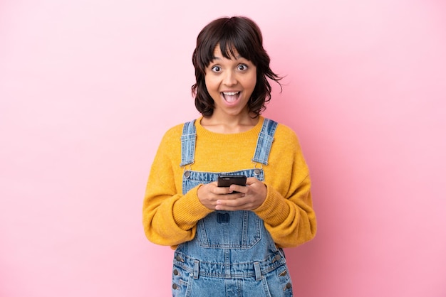 Mujer joven con un mono de fondo aislado sorprendida y enviando un mensaje