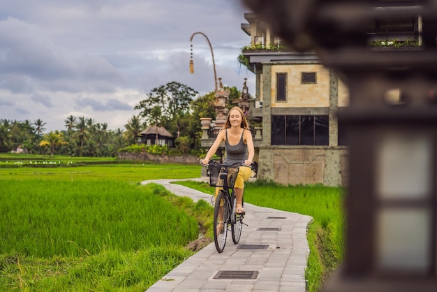 Una mujer joven monta una bicicleta en un campo de arroz en Ubud Bali Bali Travel Concept