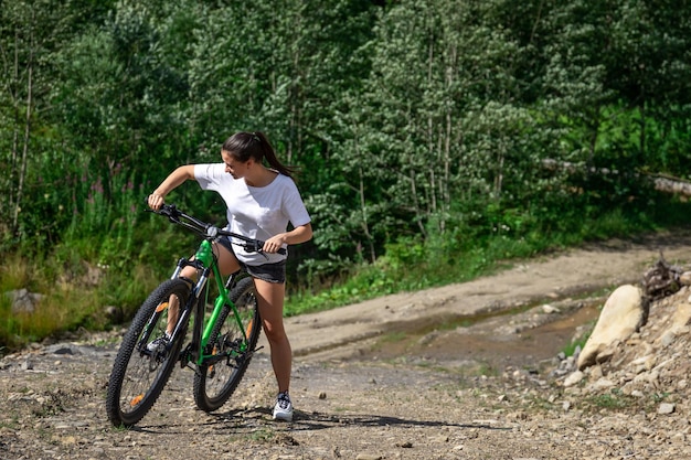 Una mujer joven monta una bicicleta en una zona montañosa del bosque.