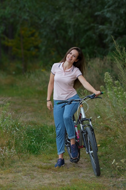 Mujer joven montando en bicicleta en el bosque. deporte, concepto de estilo de vida activo y saludable.