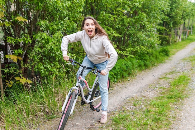 Mujer joven montando en bicicleta en el parque de la ciudad de verano al aire libre. Gente activa. Chica hipster relajarse y andar en bicicleta. Ir en bicicleta al trabajo en el día de verano. Concepto de estilo de vida de bicicleta y ecología.