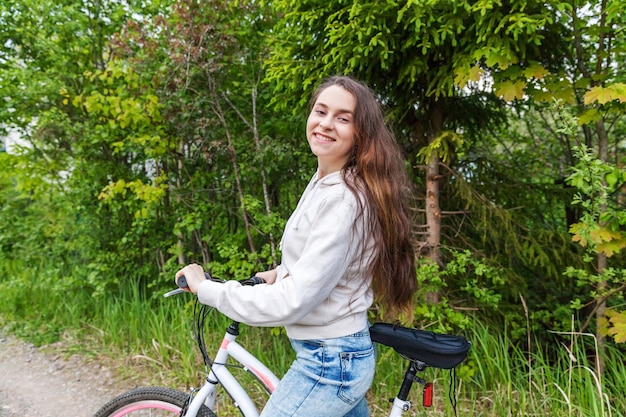 Mujer joven montando bicicleta en el parque de la ciudad de verano al aire libre Personas activas Chica hipster relajarse y andar en bicicleta