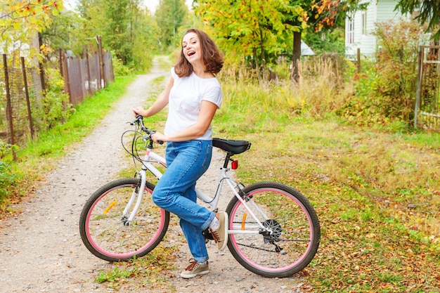 Mujer joven montando bicicleta en el parque de la ciudad de verano al aire libre. Personas activas Chica inconformista relajarse y ciclista. Ir en bicicleta al trabajo en verano. Concepto de estilo de vida bicicleta y ecología.