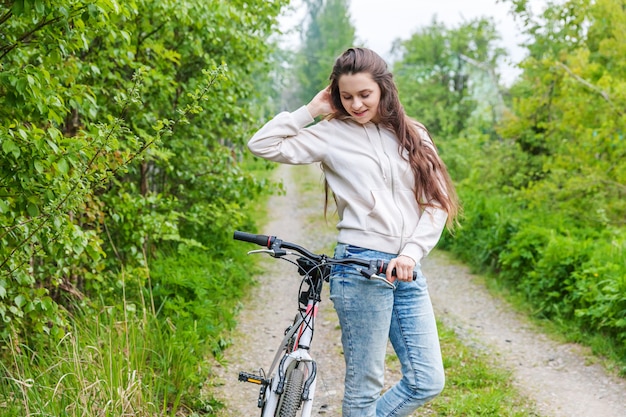 Mujer joven montando bicicleta en el parque de la ciudad de verano al aire libre. Personas activas Hipster girl relax y ciclista