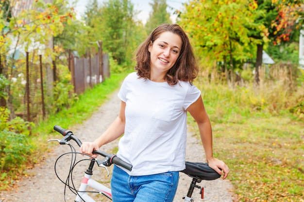 Mujer joven montando bicicleta en el parque de la ciudad de verano al aire libre