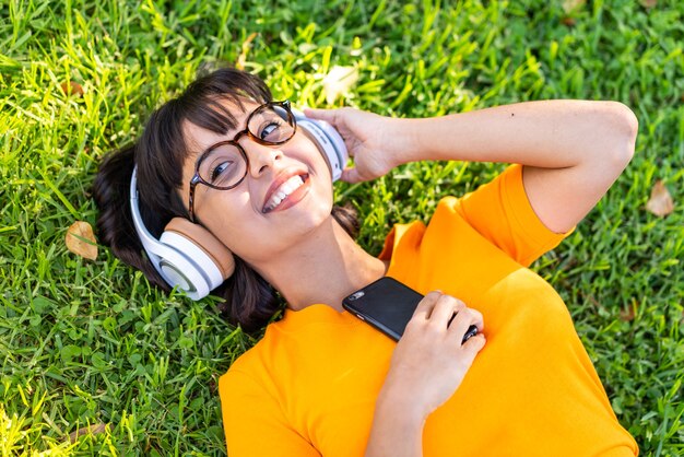 Foto mujer joven morena al aire libre escuchando música con el móvil