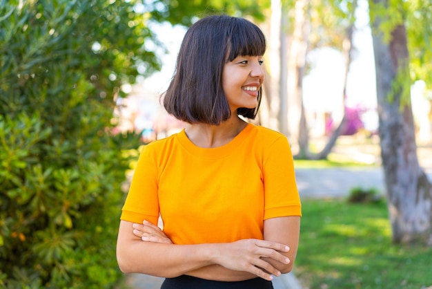 Mujer joven morena al aire libre en un parque con expresión feliz