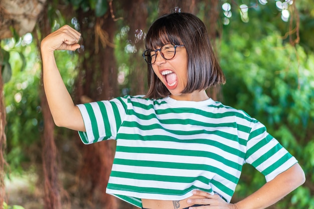 Mujer joven morena al aire libre en un parque haciendo gesto fuerte