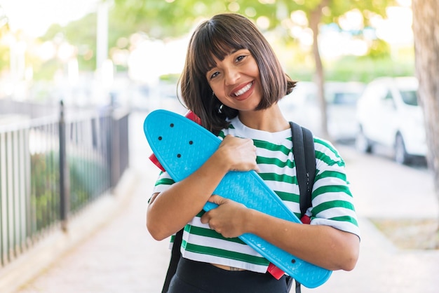 Foto mujer joven morena al aire libre con un patín con expresión feliz