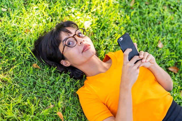 Mujer joven morena al aire libre mediante teléfono móvil